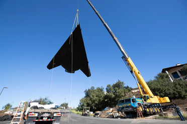 Crane lifting heavy/sepcialized freight off of a Landstar trailer.